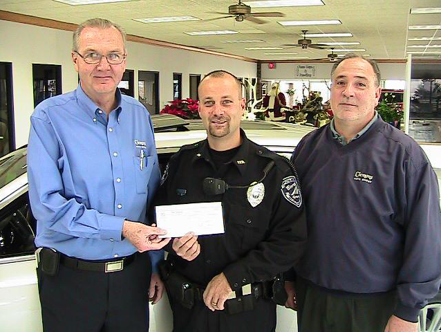 Image of Pat Clemons Inc. team members holding a caheck with a police office to show community support